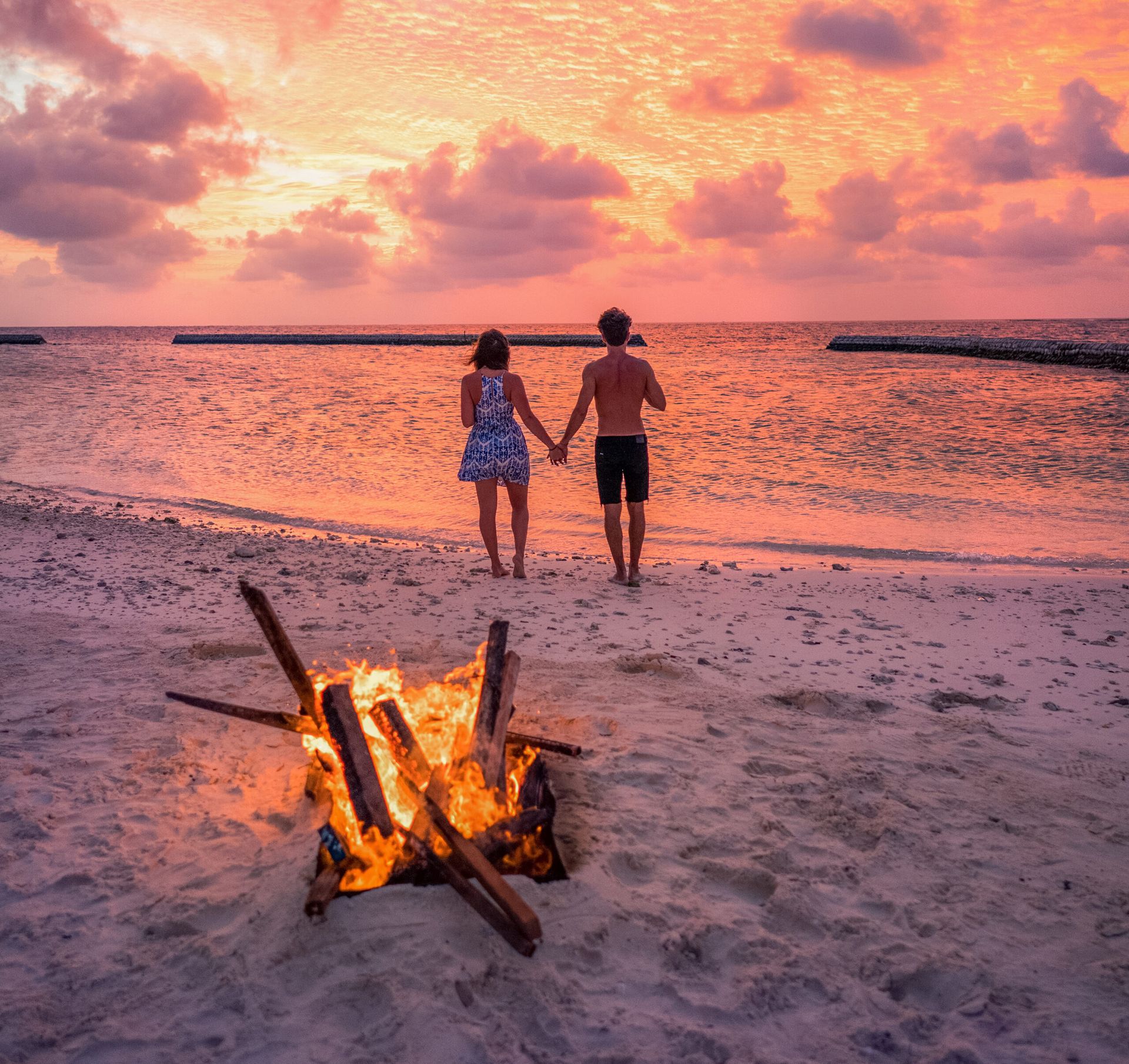 A couple holding hands while facing the beach 