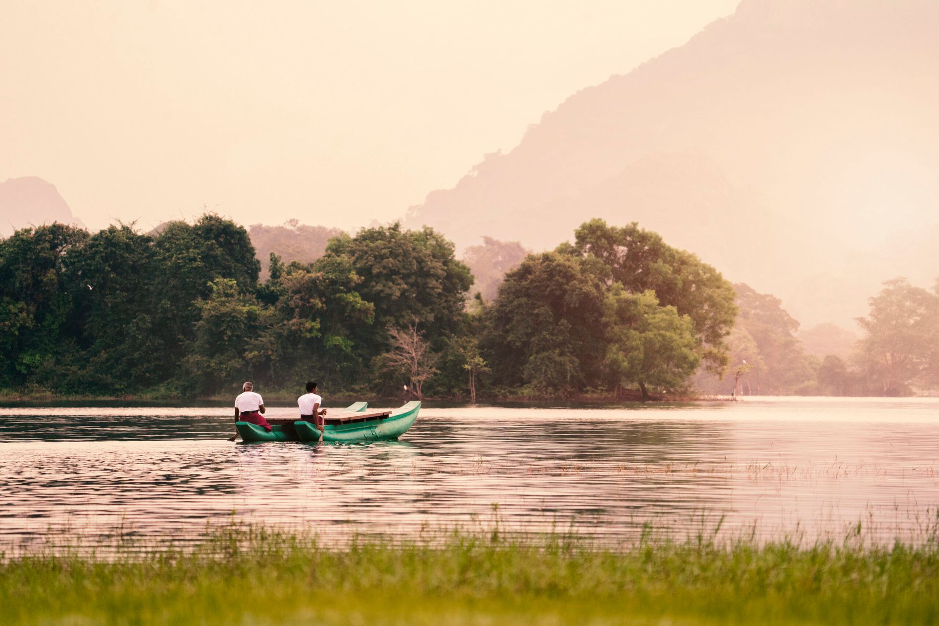 Two boatmen rowing a traditional boat on the lake