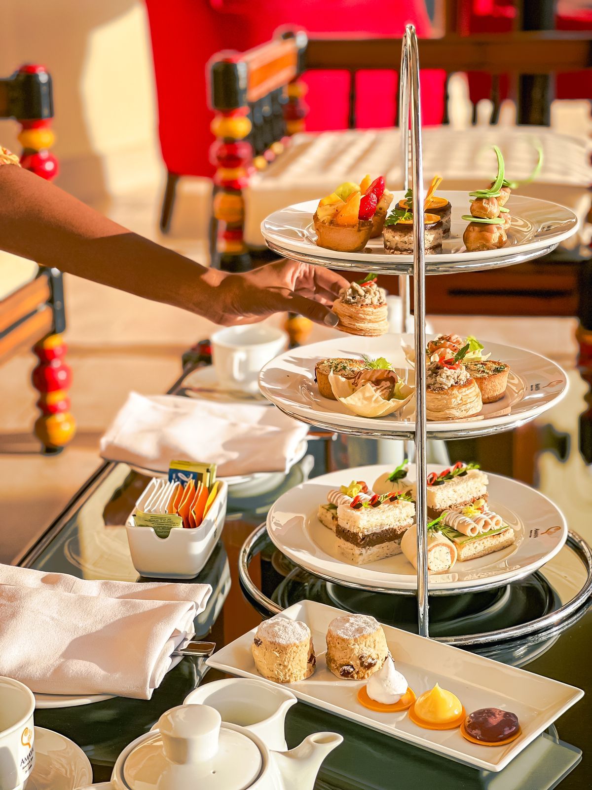 A person taking a savoury item from a high tea platter 