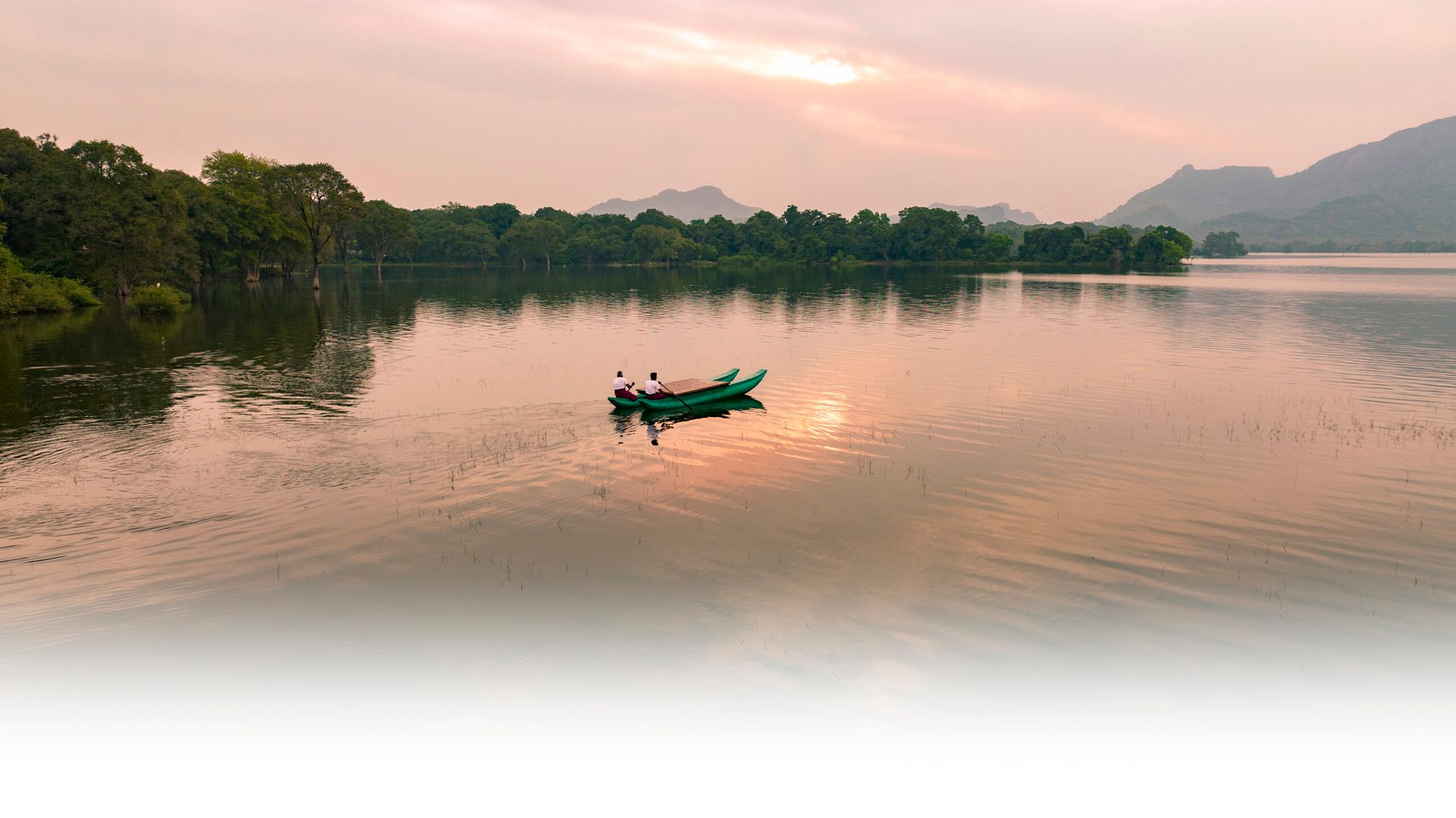 Two boatmen riding a traditional boat in the calm lake