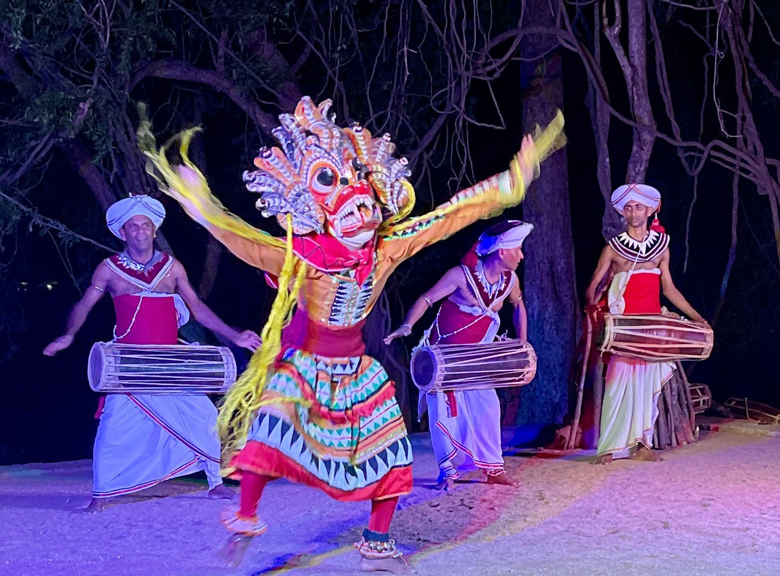 Vibrant traditional masked dancer with drummers