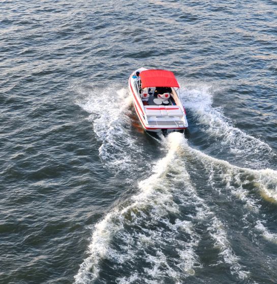 A red and white speedboat travelling across blue water.